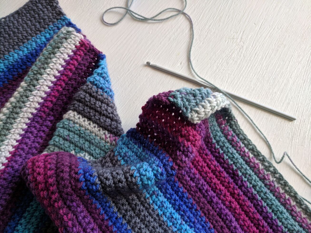 Colorful handmade crochet scarf with yarn and hook