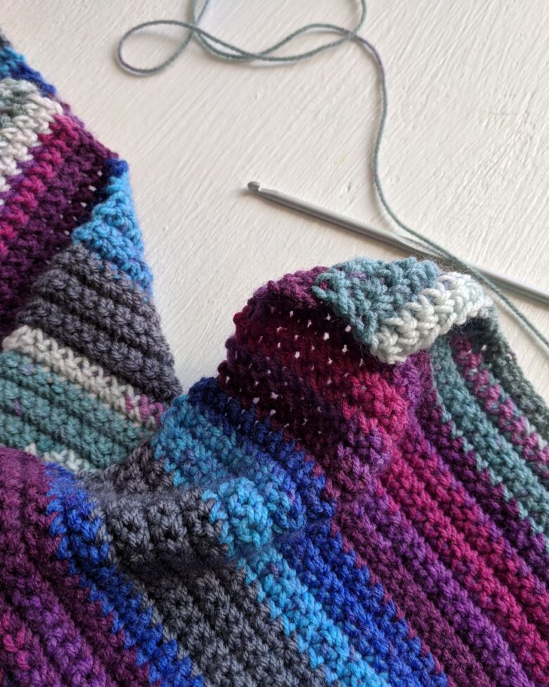 Colorful handmade crochet scarf with yarn and hook
