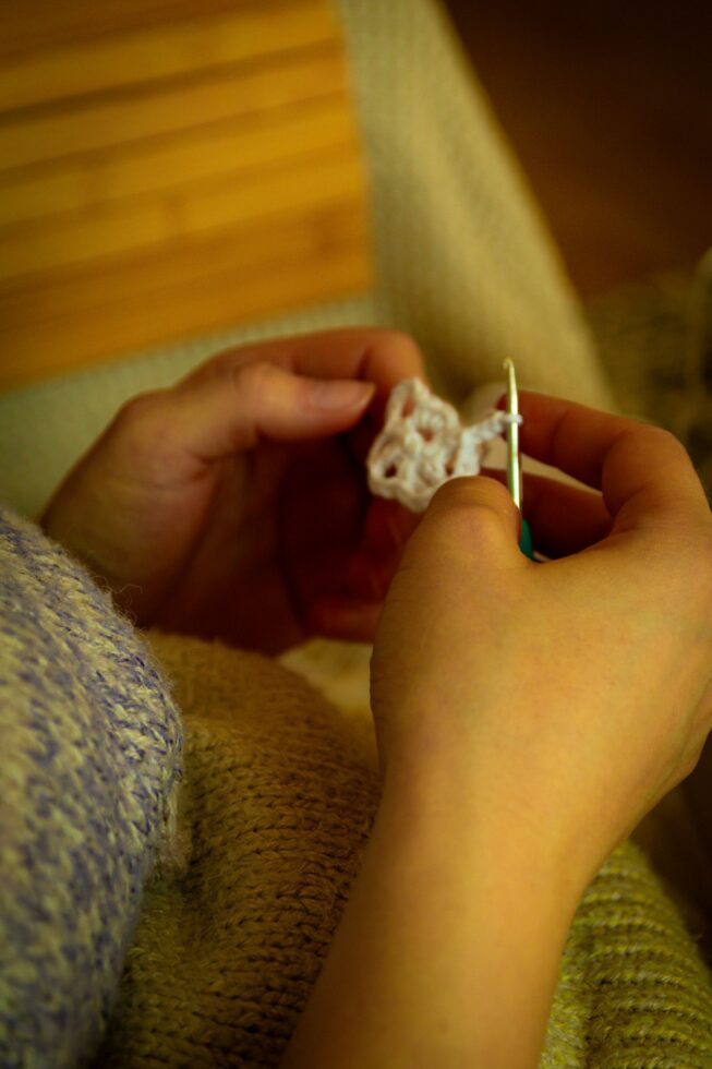 Hands crocheting along the edge of a cozy blanket
