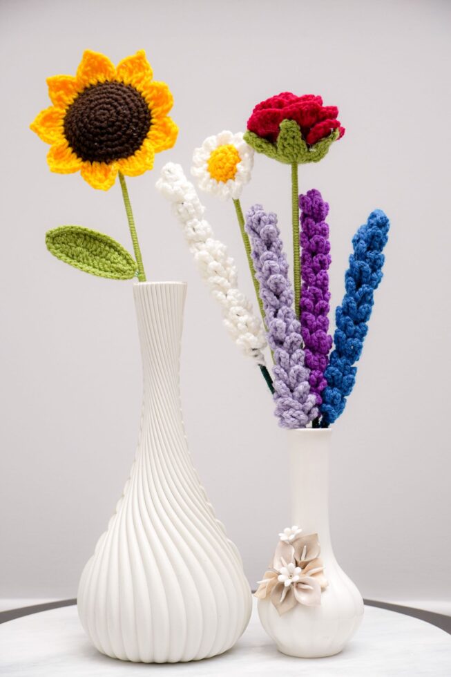 Colorful handmade crochet flowers arranged in small vases