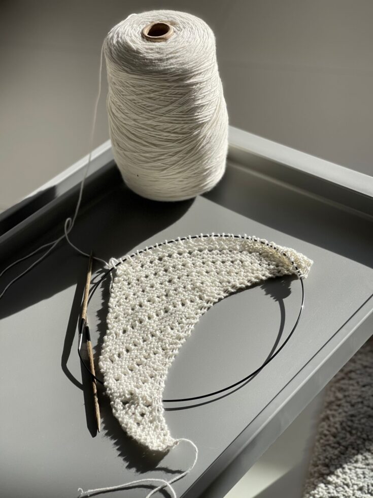 White crochet foundation in progress with a crochet hook and working yarn
