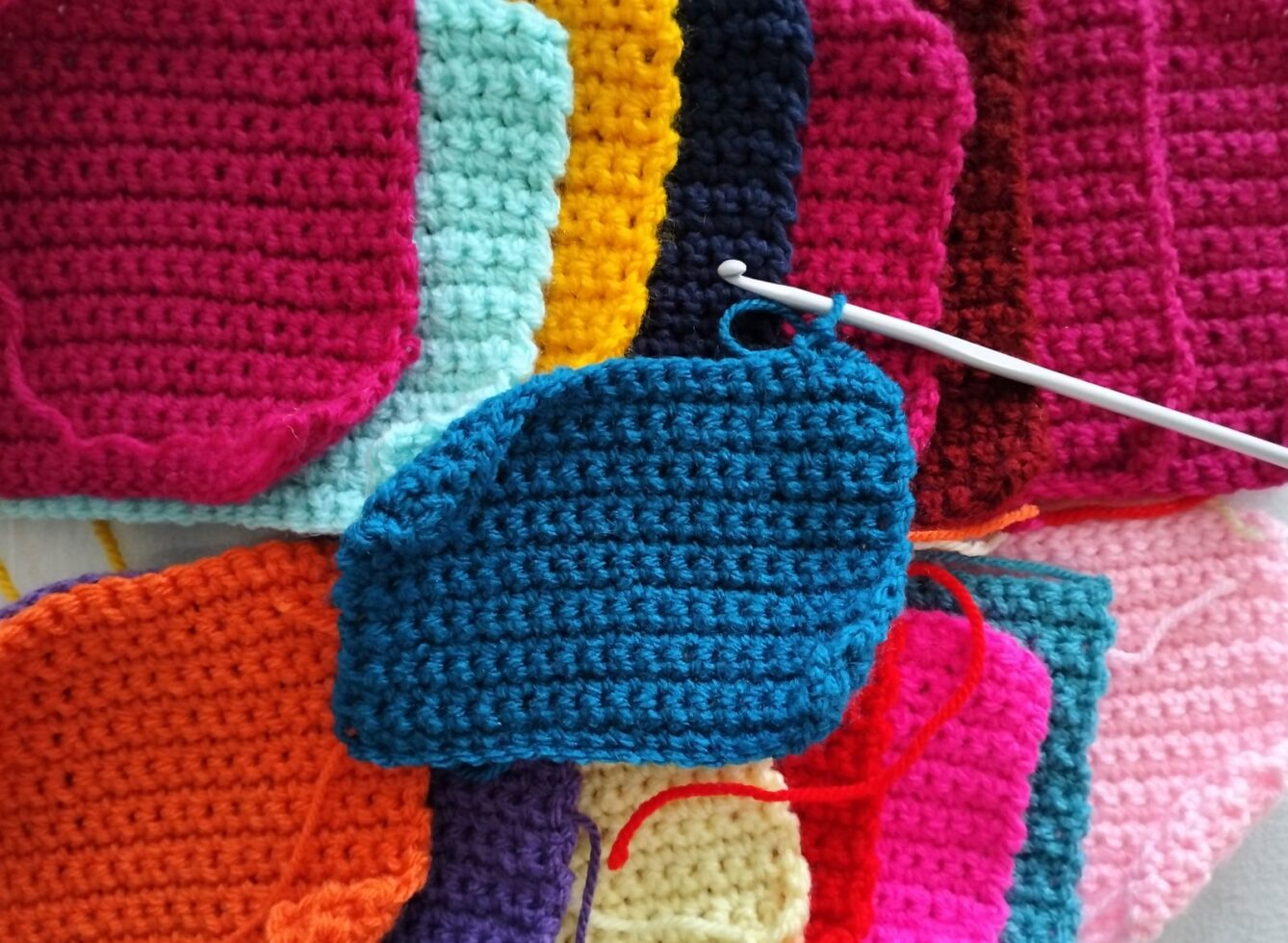 Multiple finished crochet granny squares arranged with a crochet hook