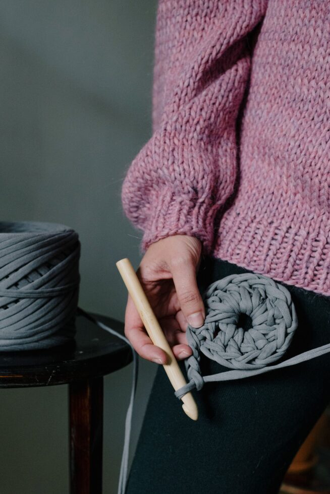 Beginner holding a crochet project with yarn and a wooden hook