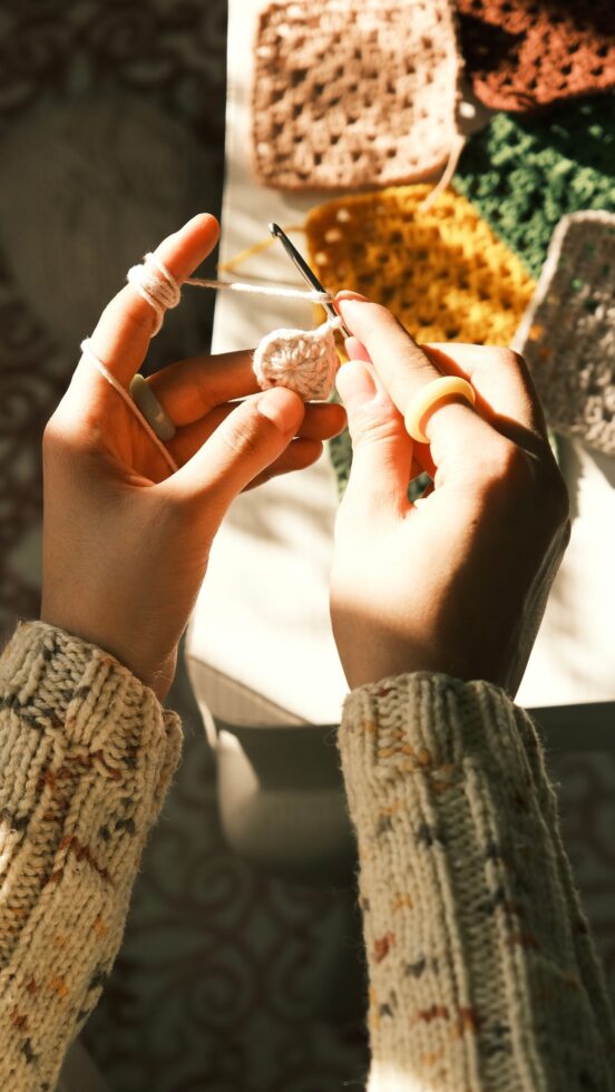 Hands crocheting a granny square in progress