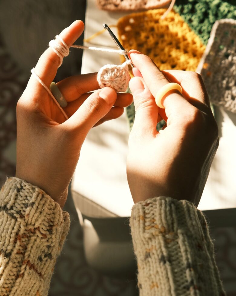 Hands crocheting a granny square in progress