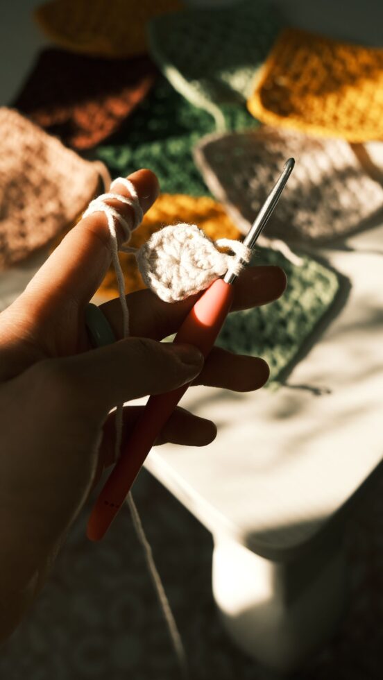 A crochet hook working along the edge of granny-square motifs