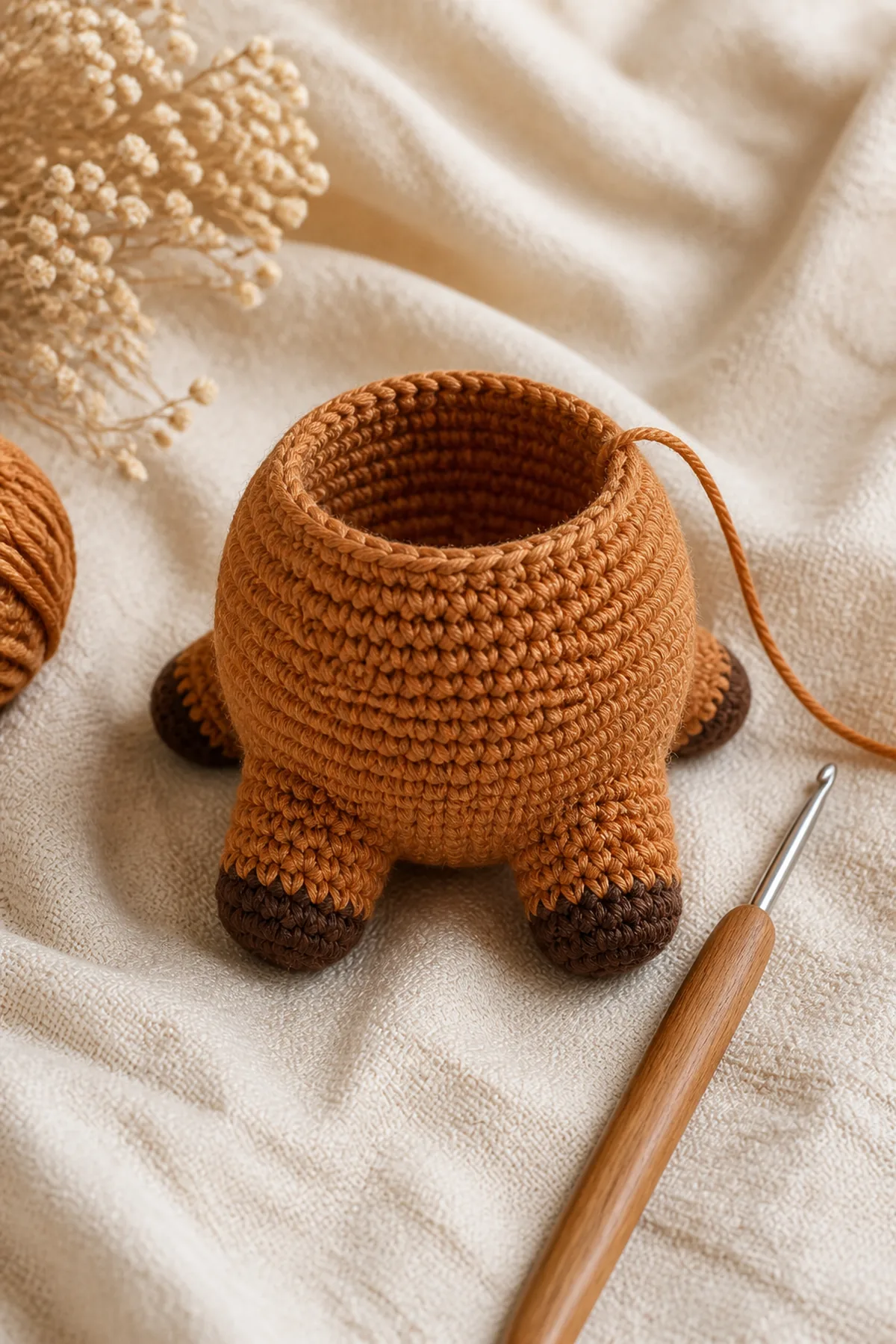 Caramel crochet cow body in progress with four dark-tipped legs