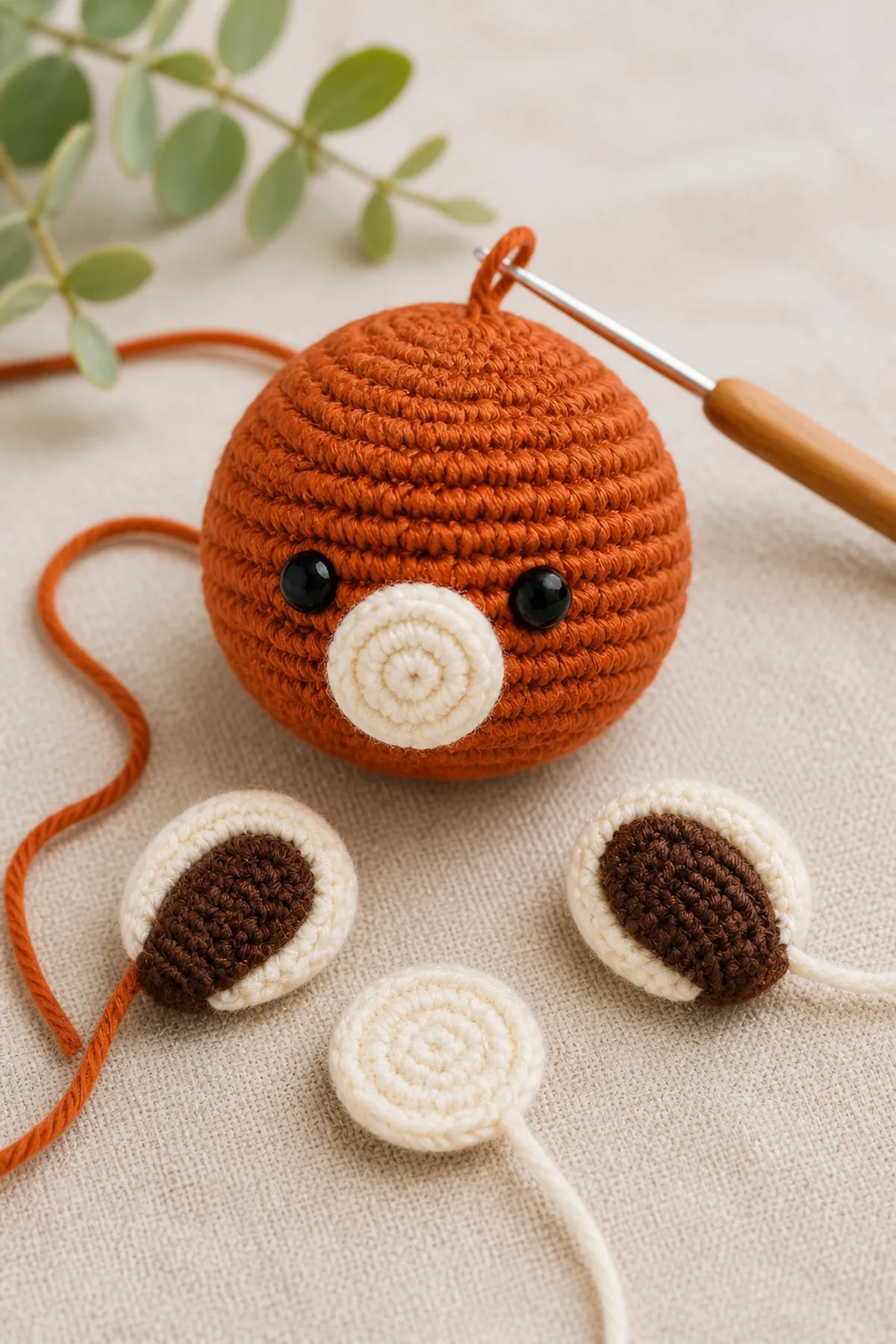 Early crochet construction stage for mini crochet red panda amigurumi with working yarn and hook